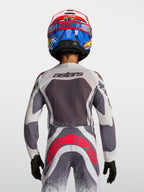 Alpinestars Supertech Swan motocross-trøje og bukser til ungdom, grå og hvid med neonrøde detaljer, set bagfra på model.