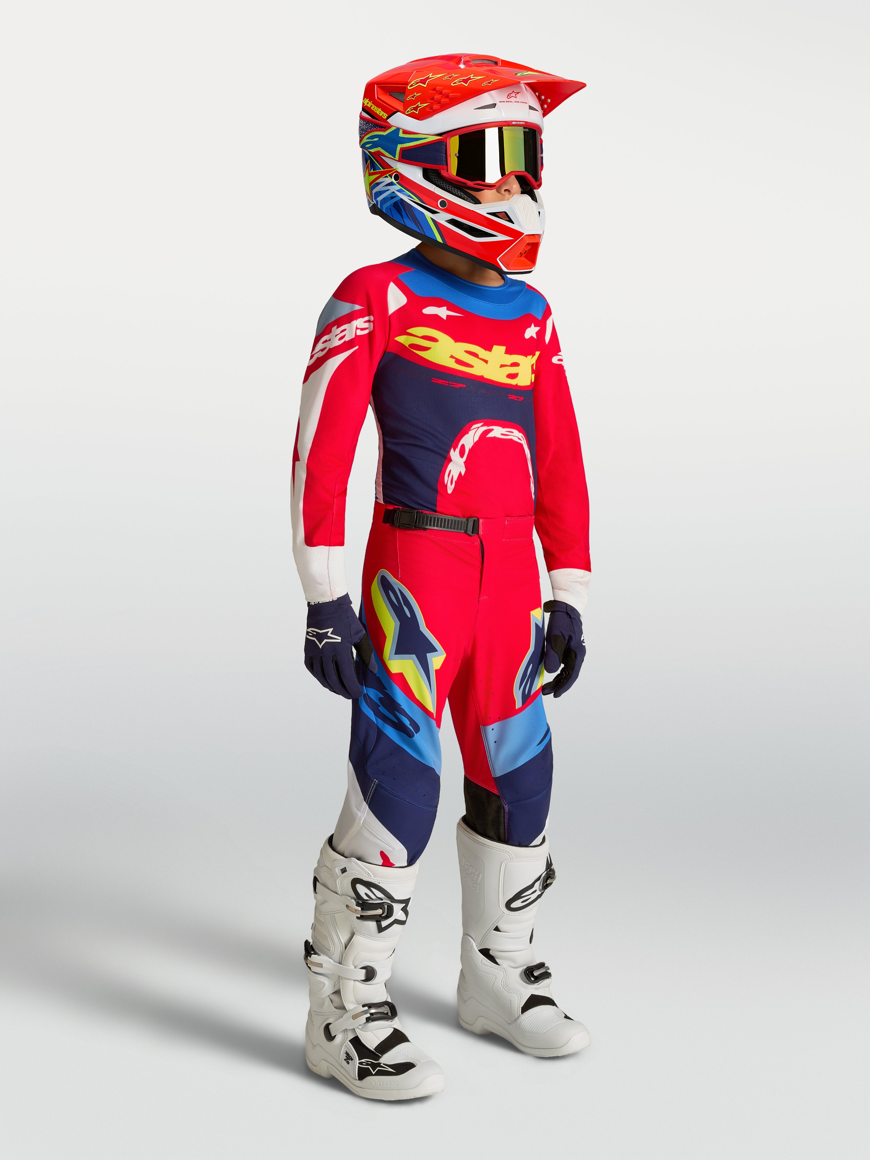 Alpinestars Youth Supertech Dyna Jersey, Fire Red and Navy Blue Motocross Gear Set on a young rider with white boots.