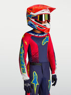 Alpinestars 2027 Fluid Drag trøje ungdom, motocrosstrøje i marineblå og rød, båret af ung rytter med matchende racerhjelm.