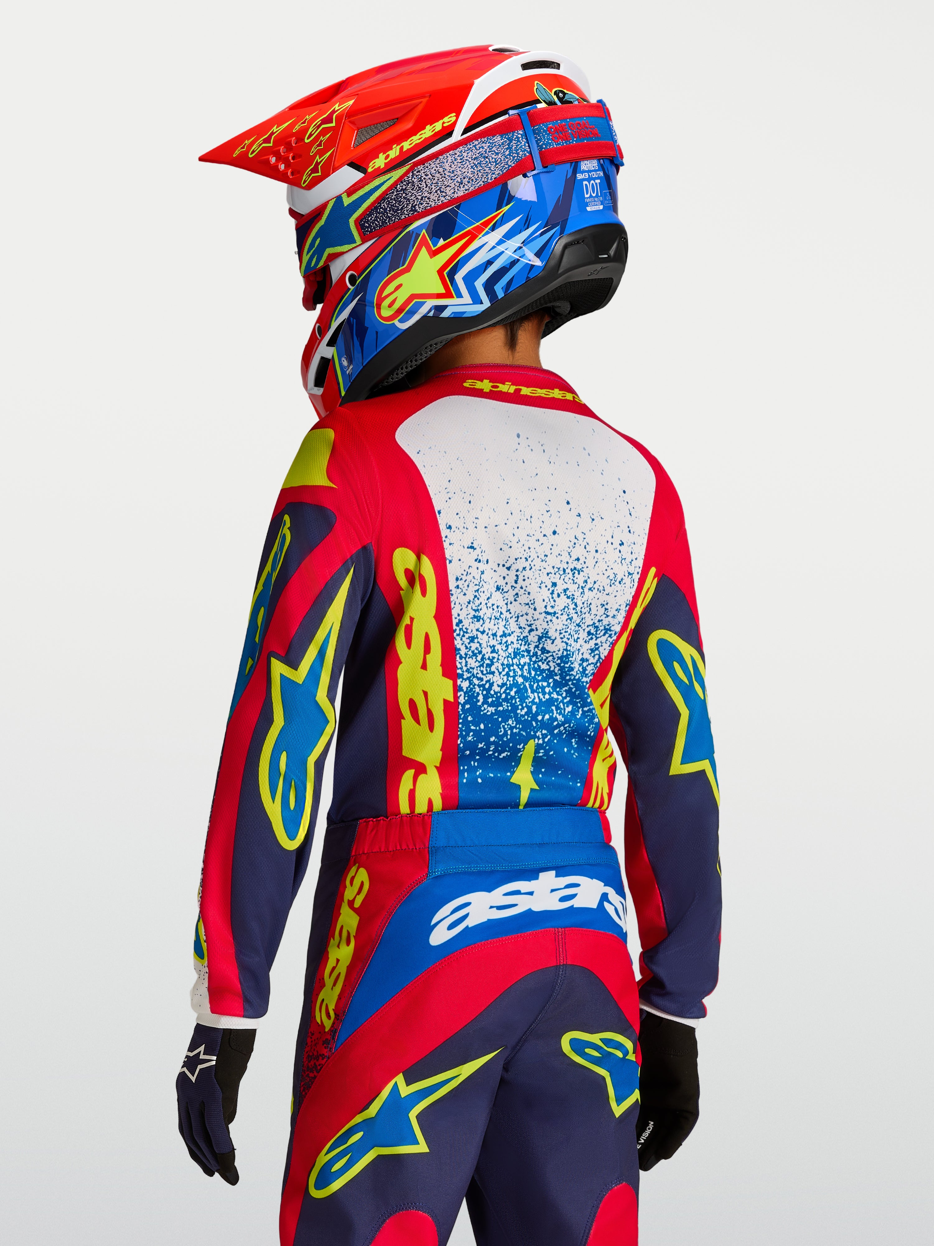 Alpinestars 2027 Fluid Drag Trøje Ungdom, rød og mørkeblå motocrosstrøje med gul grafik, set bagfra på en rytter