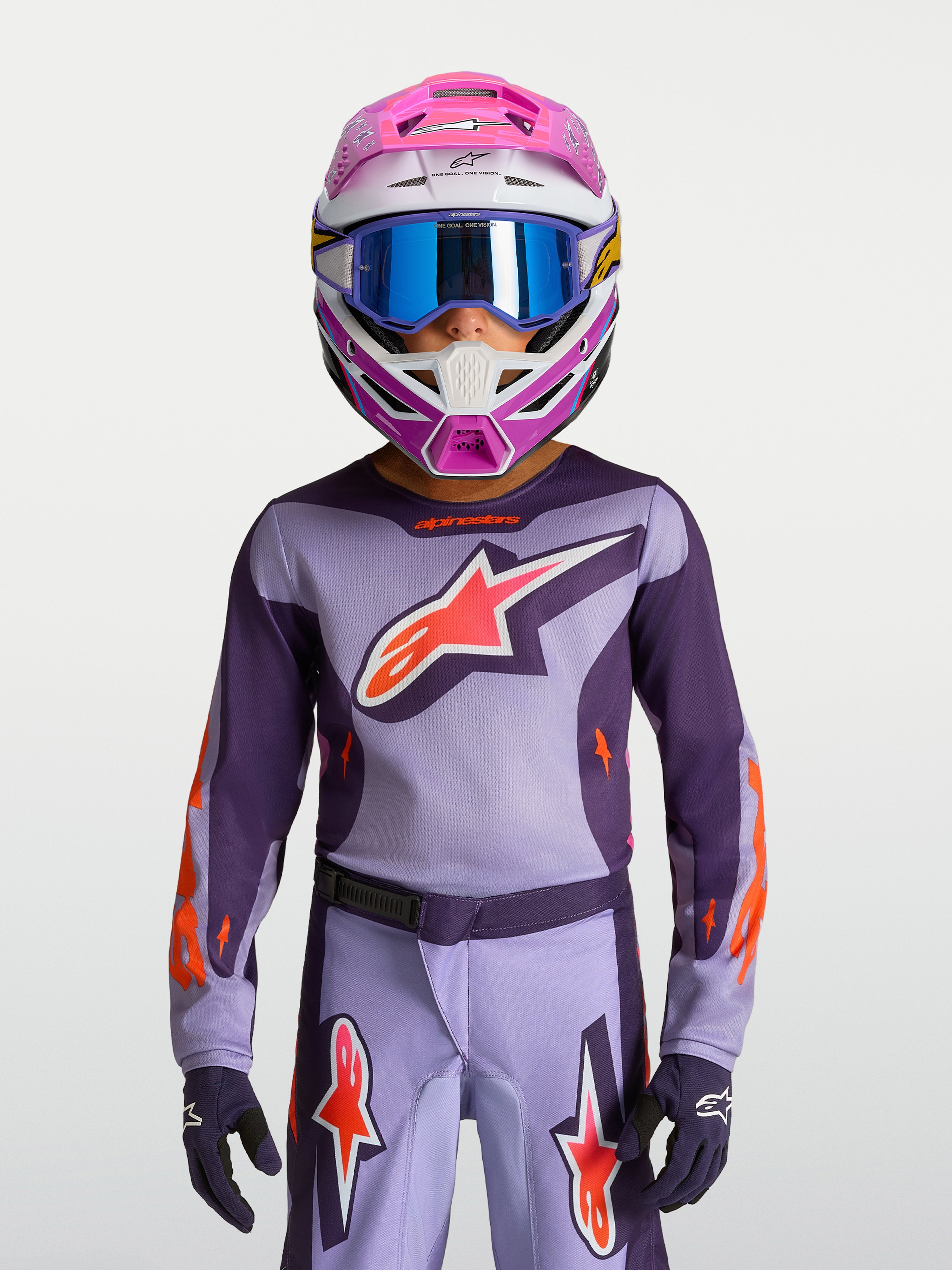Alpinestars 2027 Fluid Hunt trøje ungdom, lilla og pink motocrossudstyr til børn, vist med racerhjelm og goggles.