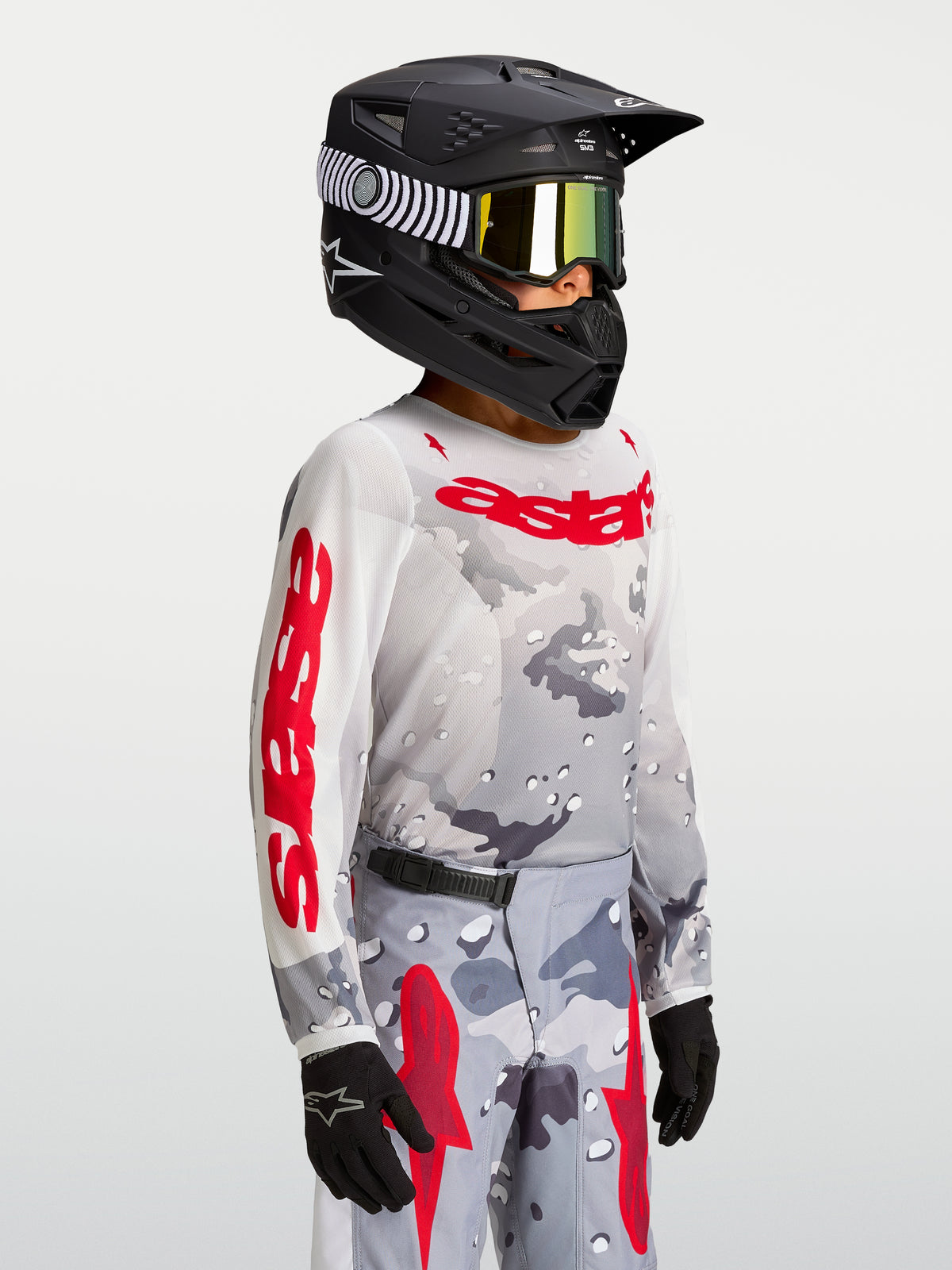 Alpinestars 2027 Youth Fluid Lone Jersey, youth motocross jersey in gray camo and fire red, worn on-model with a helmet.