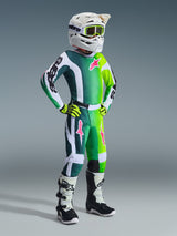 Ung motocrossrytter iført komplet racerudstyr, Alpinestars 2026 Youth Fluid Portl-trøje i grøn gradient med hvide og sorte detaljer, med lyserøde logoer, matchende bukser, hvid hjelm med neongule briller, neongule handsker og hvide og sorte støvler, koordineret outfit til off-road kørsel