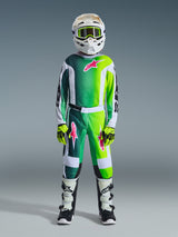 Motocross-rytter iført komplet racerudstyr, 2026 Youth Fluid Portl Jersey i grøn, hvid og sort med lyserødt logo, matchende bukser, hvid hjelm med gule briller, hvide og sorte støvler, limegrønne handsker, koordineret sæt til off-road kørsel for unge