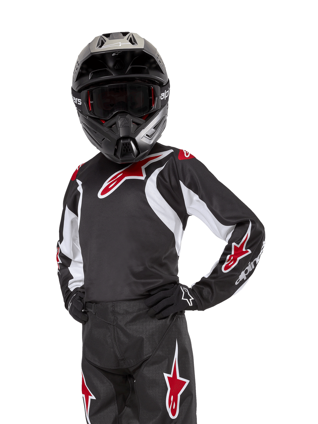Alpinestars Youth 2024 Racer Lucent Jersey, motocross-trøje, sort, hvid og rød, båret af en ung rytter med en sort hjelm og matchende bukser, med røde stjernelogoer og hvide grafiske detaljer, højtydende off-road-beklædning til motocross-løb