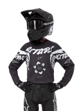 Alpinestars 2024 Youth Racer Hana trøje, motocross-trøje til unge, sort med hvid grafik og logoer, vist med sort hjelm og handsker, holdbart og let materiale til terrænkørsel