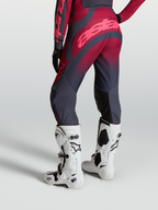 Alpinestars Stella Techstar Swan motocrossbukser til kvinder, grå og rød, set bagfra med hvide Tech 10 støvler.