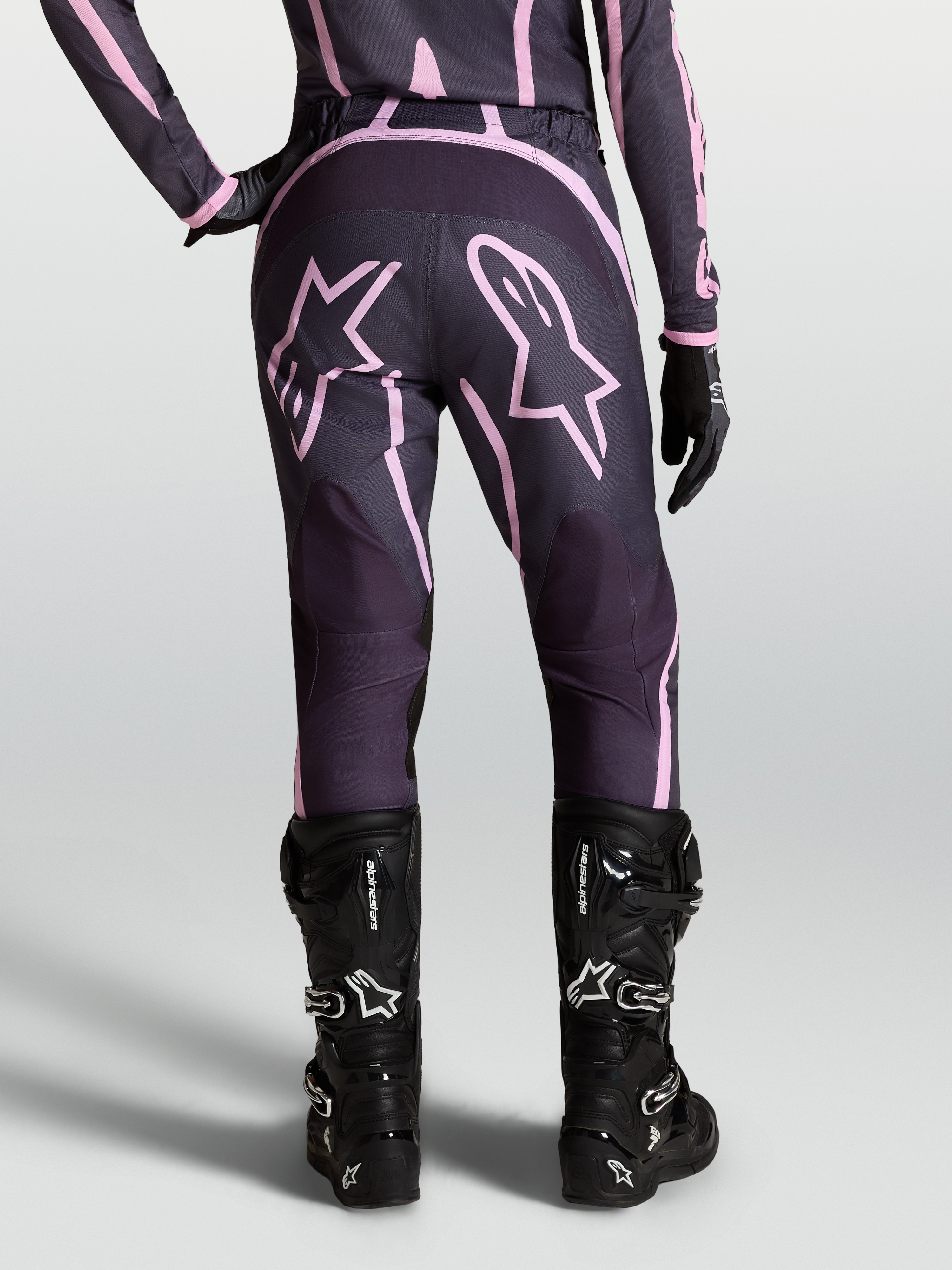 Alpinestars Stella Fluid Apex V2 Pants, Women's Motocross Pants in Graystone and Pink with Star graphics and black boots.