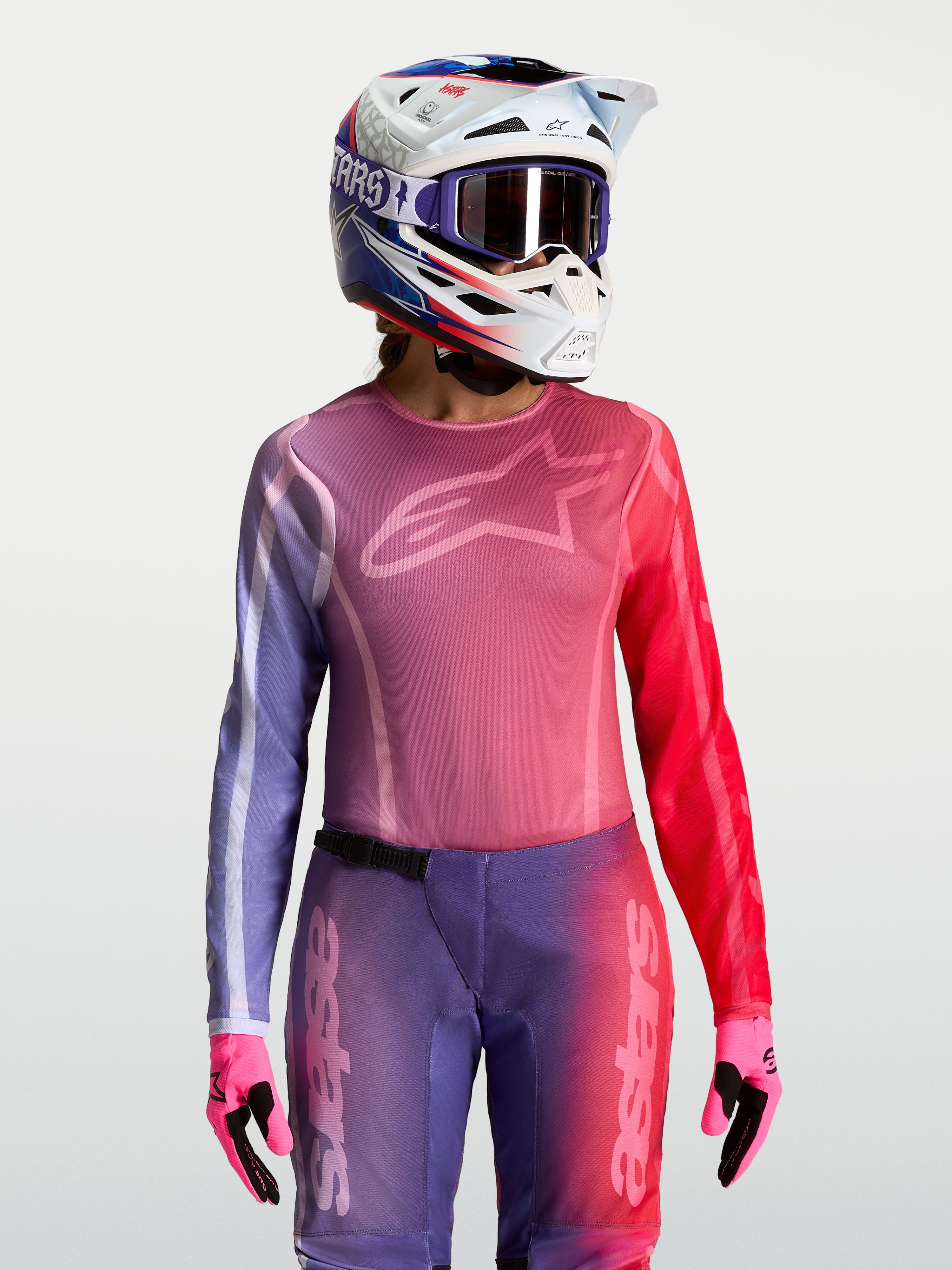 Alpinestars Stella Fluid Kepler trøje til kvinder, lilla og rød motocross-jersey med atletisk pasform, vist sammen med matchende MX-hjelm og handsker.