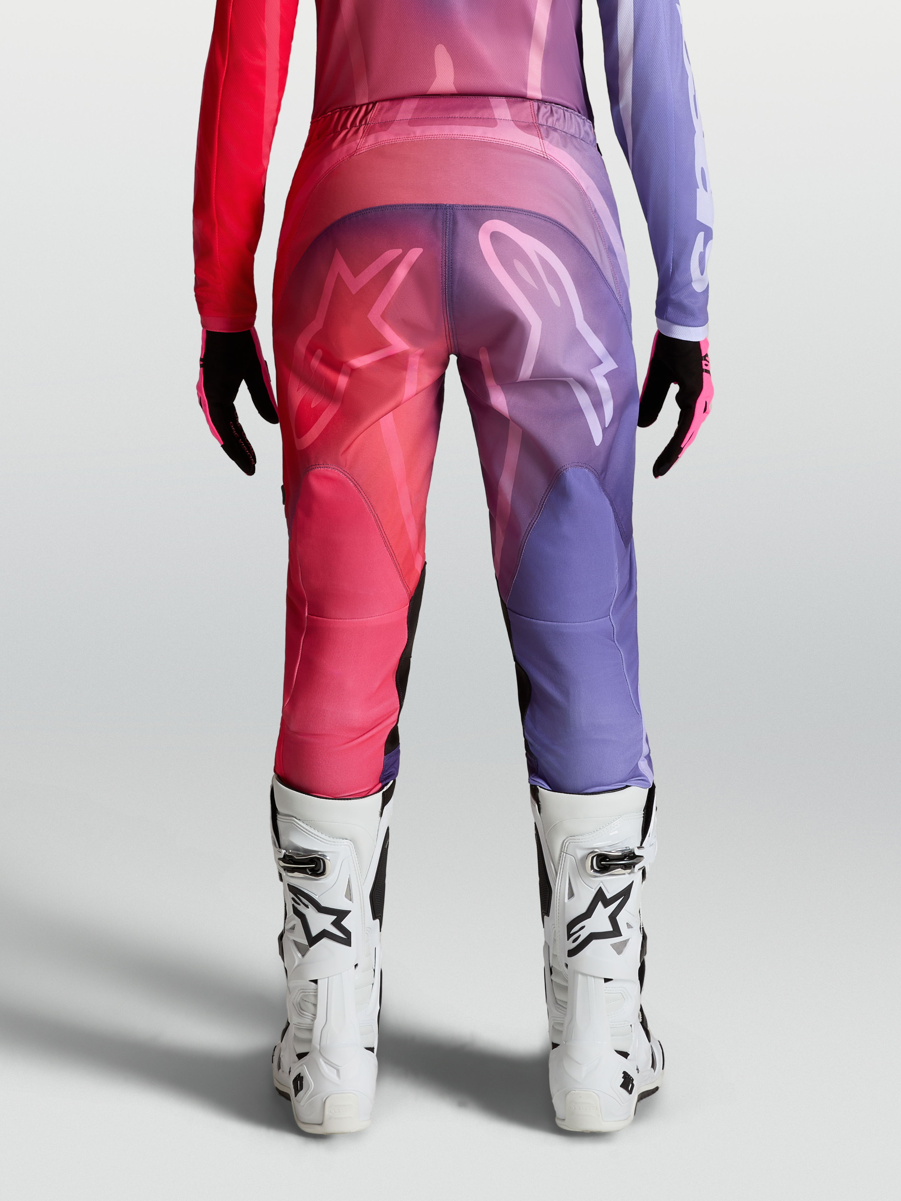 Alpinestars Stella Fluid Kepler Bukser, dame-motocrossbukser i lilla og rød, set bagfra med hvide støvler, præformet ergonomisk pasform.