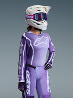Alpinestars 2026 Stella Fluid Apex Gear Set til damer, lilla og lavendelfarvet motocross-trøje og bukser, båret af en kører med hvid hjelm og lilla goggles, med markant hvid Alpinestars-branding og logoer