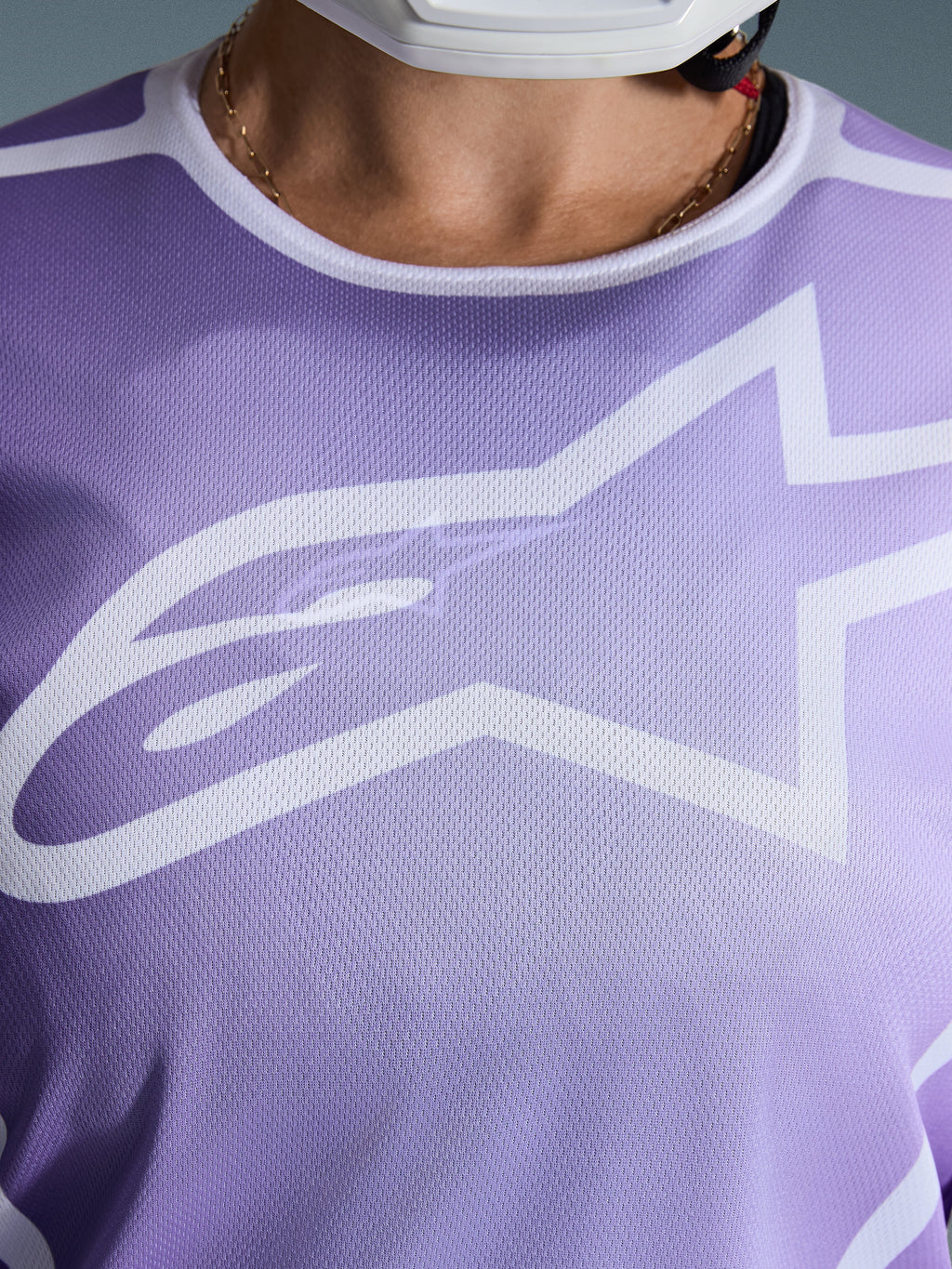 Alpinestars 2026 Stella Fluid Apex trøje, nærbillede af brystet, lilla med hvid grafik, stort hvidt Astars-logo, åndbar mesh-polytekstilkonstruktion, motocross-udstyr til damer