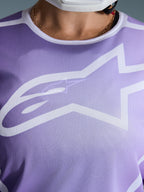 Alpinestars 2026 Stella Fluid Apex trøje, nærbillede af brystet, lilla med hvid grafik, stort hvidt Astars-logo, åndbar mesh-polytekstilkonstruktion, motocross-udstyr til damer