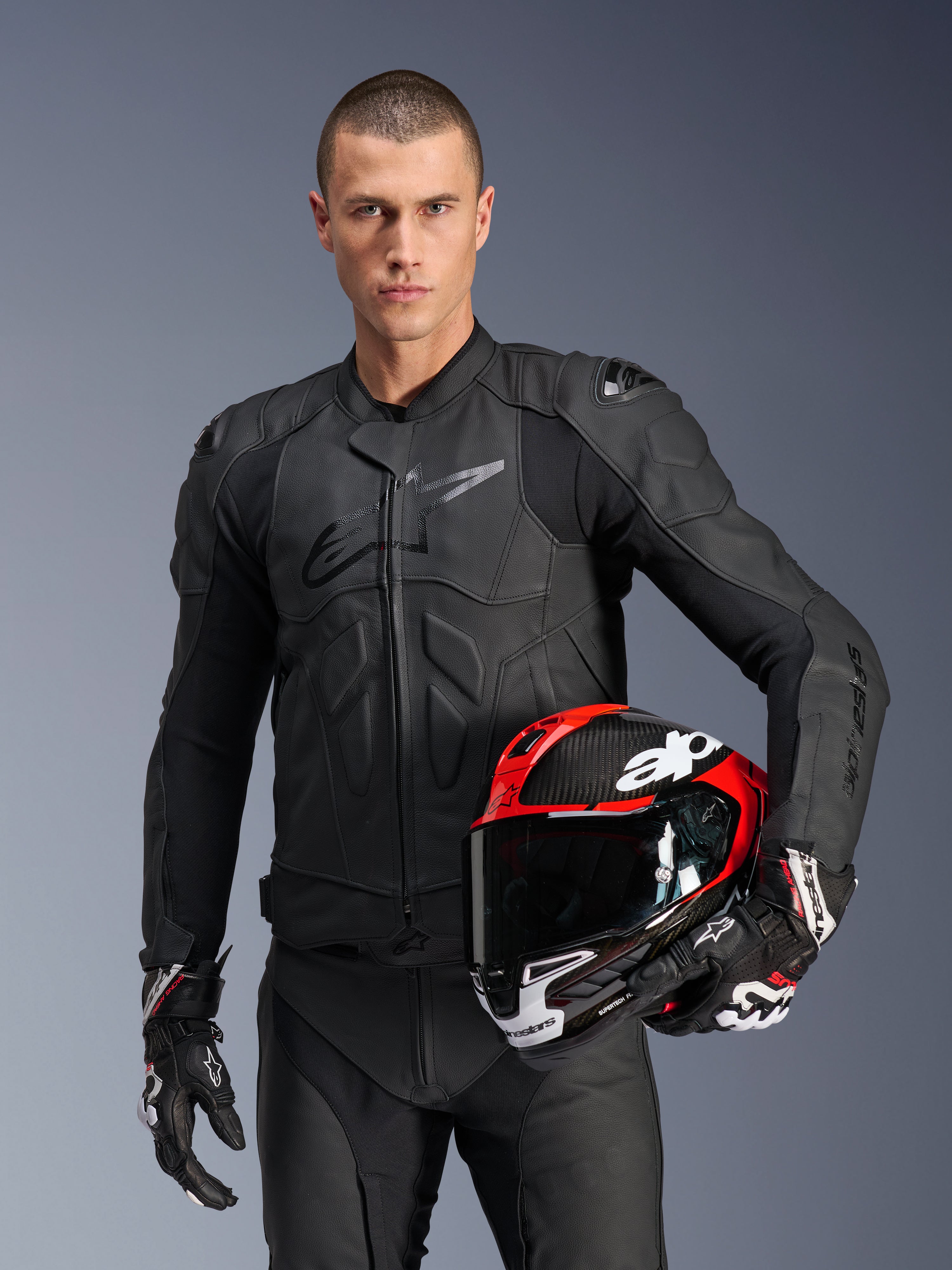 Alpinestars Dusk læderjakke, sort herre-motorcykeljakke i læder med Nucleon PLASMA beskyttelse og rød racerhjelm.