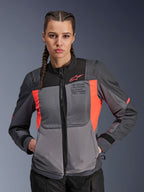 Alpinestars Stella ST-2 Air-jakke, motorcykeljakke til damer, mørkegrå og Fluo Coral, båret af model med flettet hår, med tekniske mesh-paneler for luftstrøm, laserperforeringer og 'Alpinestars Exploration Equipment'-branding på brystet, sommer-touringudstyr