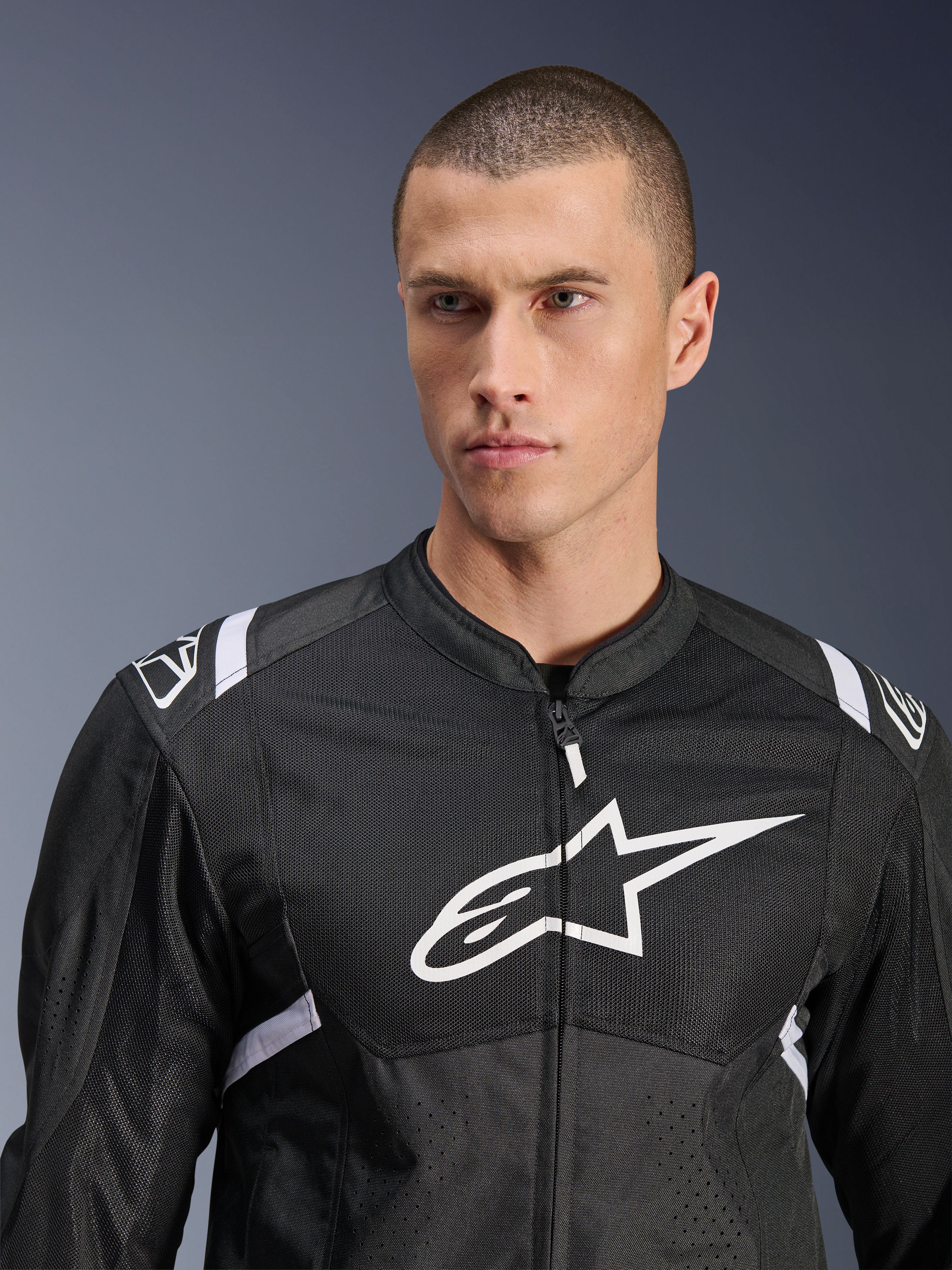 Alpinestars T-SPS Air V2-jakke, tekstil motorcykeljakke, sort og hvid, med stort hvidt logo på brystet og mesh-paneler, sportslig pasform båret af mandlig model