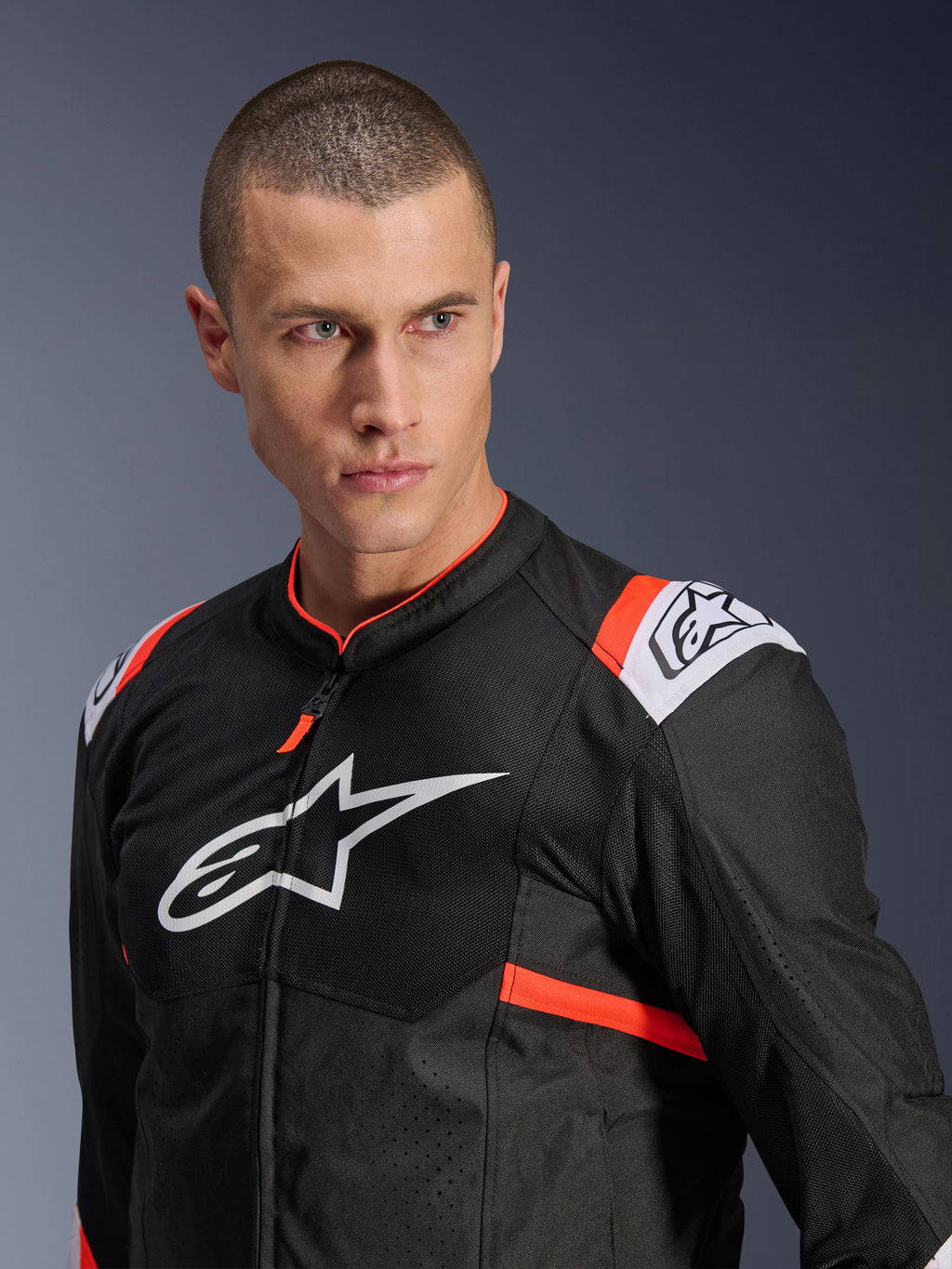 Alpinestars T-SPS Air v2 jakke, sort med hvide og røde fluo-detaljer, mesh-tekstilkonstruktion for optimal luftstrøm, stort hvidt Alpinestars-logo på brystet, vist på model, urban sport-kørestil