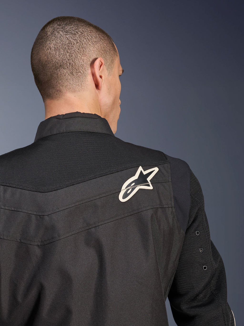 Alpinestars T-Dyno Air Jakke, sort tekstil motorcykeljakke, nærbillede bagfra der fremhæver det åndbare 3D-mesh-bærestykke og ærmerne, hvidt og sort stjernelogo på højre skulder