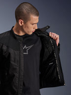 Alpinestars T-Dyno Air jakke, sort, mandlig model der viser det indvendige mesh-for og mærkatet for det vandtætte rum, båret over en sort t-shirt med grafik, moderne urbant motorcykeludstyr