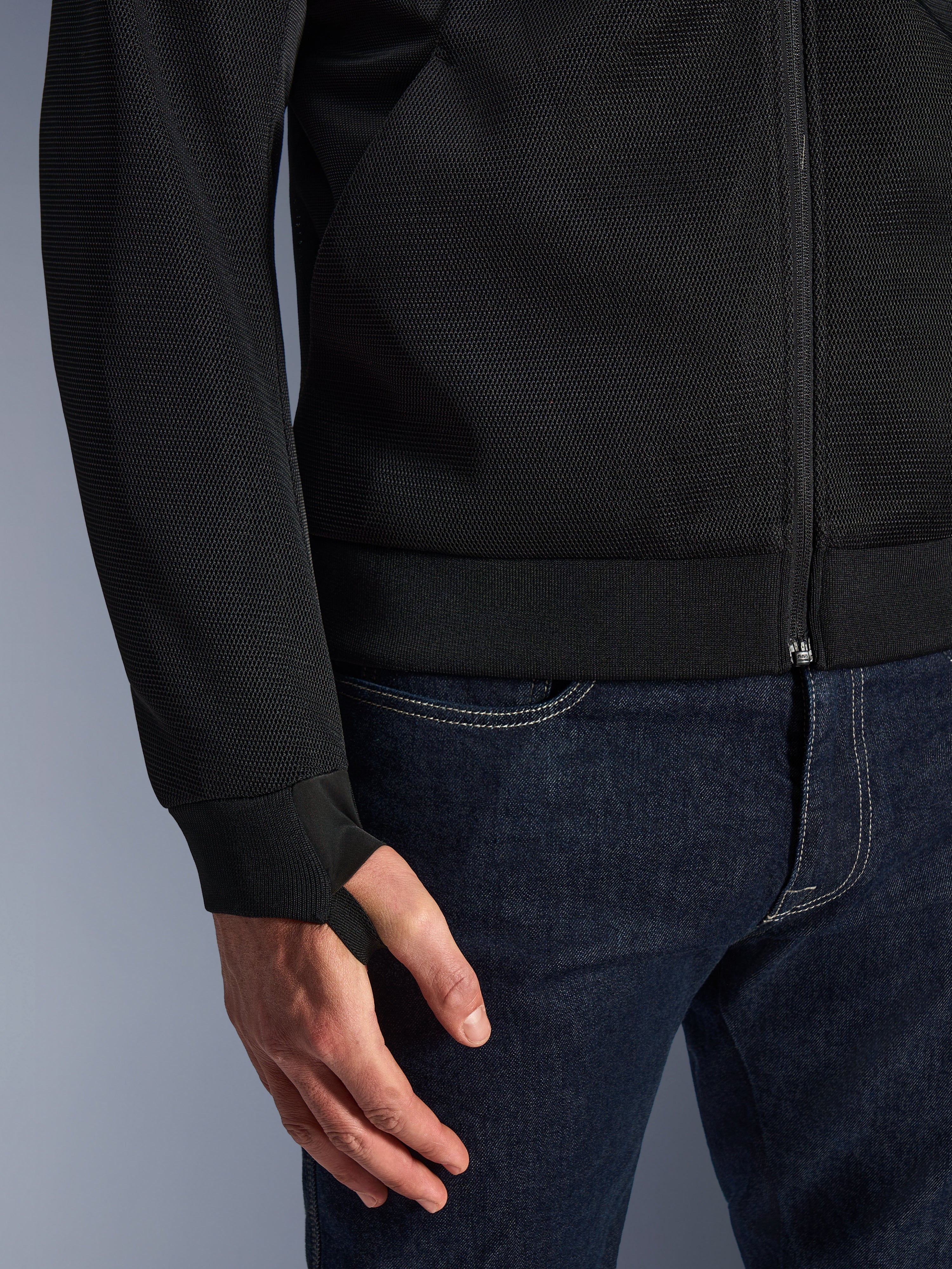 Alpinestars Chrome Superairflow Hoodie, sort, nærbillede af højmodstandsdygtigt 3D teknisk mesh-stof, med ribbet stretch jersey-manchet og elastisk tommelfingerløkke, båret med blå jeans