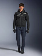 Motorcykelrytter iført Alpinestars Chrome Superairflow Hoodie i sort og grå, kombineret med mørkeblå jeans, sorte motorcykelhandsker og sorte sko. Hættetrøjen har et stort stiliseret logo på brystet og en 3D-mesh-tekstur til ydeevne ved høje temperaturer.