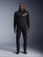 Alpinestars Chrome V2 Sport Hoodie, sort og hvid motorcykel-hættetrøje, med et stort hvidt Alpinestars-logo på brystet, lynlås foran og hætte, båret af en model i sorte bukser og støvler, beskyttende køreudstyr i urban stil.