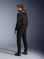 Alpinestars Chrome Air Sport Hoodie, urban motorcykel-hættetrøje, sort og rød fluo, set bagfra med rødt Alpinestars-branding på hætten og mesh-sidepaneler, båret med sorte kørebukser og teknisk fodtøj