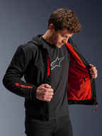 Alpinestars Chrome Air Sport Hoodie i sort og rød fluo, mandlig model der åbner jakken for at fremvise det klare røde mesh-for, Alpinestars-branding på højre ærme og brystlynlås, afslappet urban motorcykeljakke designet til luftgennemstrømning