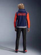 Model set bagfra iført Alpinestars MM93 Chrome V2 Sport Hoodie, mørkeblå med stærke neonrøde ærmer og grå melerede detaljer, store MM93 og Marc Marquez logoer på ryggen og hætten, afslappet motorcykel-hættetrøje kombineret med sorte bukser
