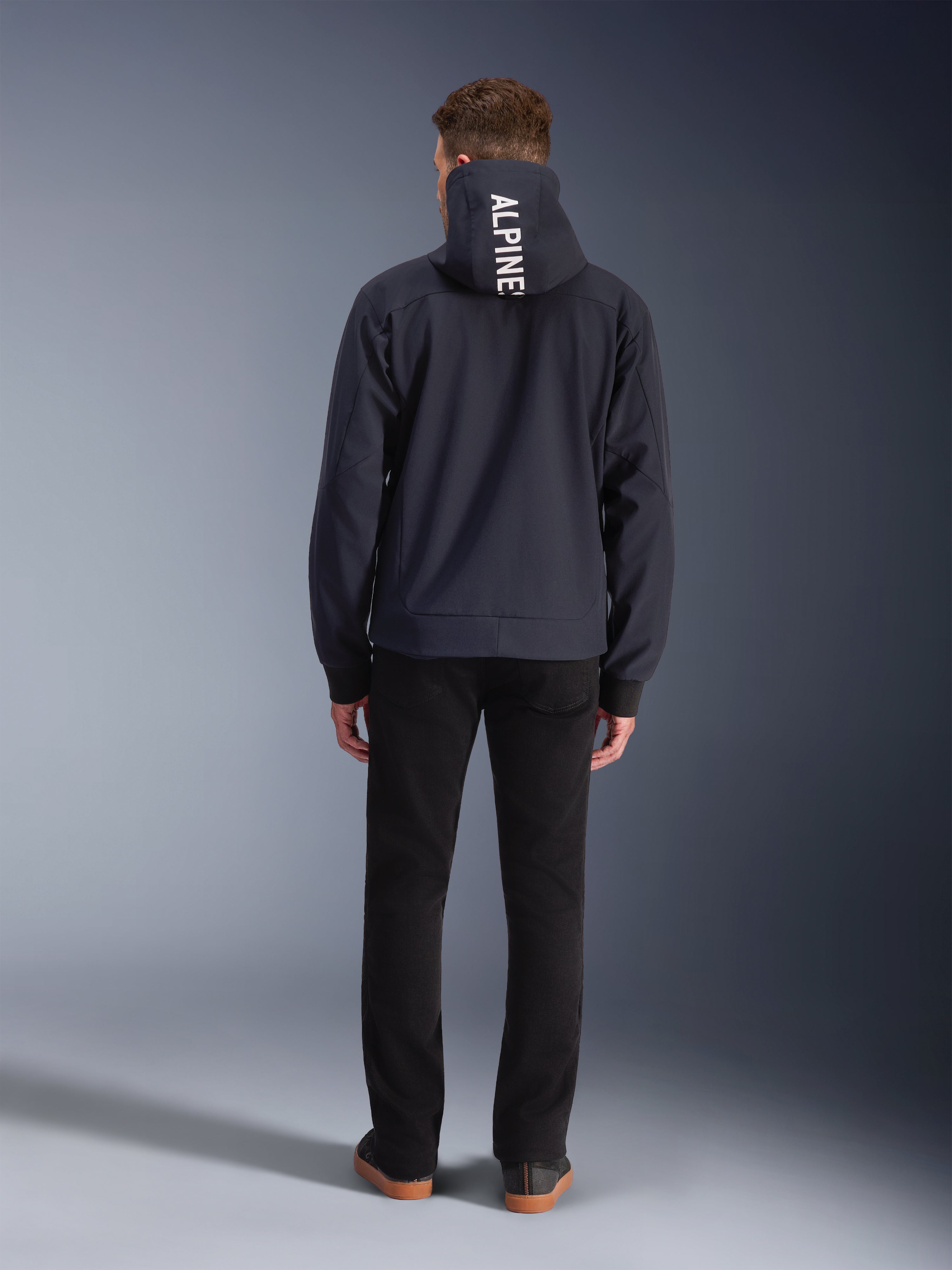 Alpinestars Radium Tech hættetrøje, sort vindtæt urban motorcykeljakke til mænd med hvidt logo på hætten, set bagfra.