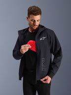 Alpinestars Radium Tech hættetrøje, sort urban motorcykeljakke til herrer, mand holder en rød Nucleon Flex Plus beskyttelsesindsats, CE-certificeret tekstiljakke med hvidt logo, Tech-Air® ready.