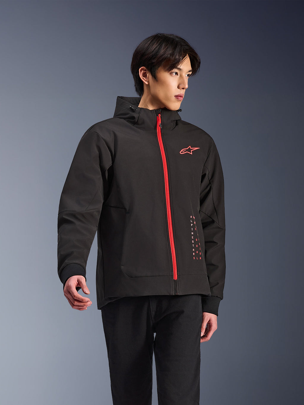 Alpinestars Radium Tech Hoodie, urban motorcykeljakke, sort med klar rød lynlås, med rødt Alpinestars-logo på brystet og rød tekst på siden, teknisk vindtæt skal med hætte og ribbede manchetter, moderne street-stil til motorcyklister