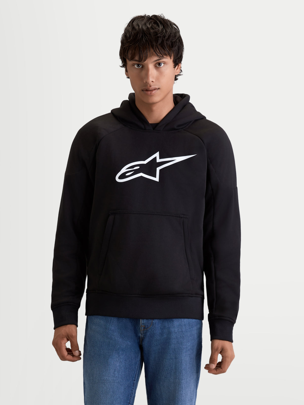 Alpinestars Ageless Hættetrøje, herre urban motorcykelhættetrøje i sort med hvidt logo på brystet, frontkængurulomme og afslappet tekstilkonstruktion, set forfra på mandlig model