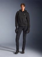 Kvindelig model iført Alpinestars Stella Chrome Superairflow Hoodie i sort, kombineret med sorte tekniske kørebukser og handsker, med 3D-mesh tekstilkonstruktion og kobberfarvet logo på brystet, urban sport-motorcykelbeklædning til kvinder.