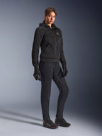 Kvindelig kører iført Alpinestars Stella Chrome Superairflow Hoodie i sort, teknisk motorcykel-hættetrøje med 3D-mesh-konstruktion, kombineret med sorte kørebukser, handsker og køresko i atletisk stil, urban sportsæstetik