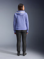 Alpinestars Stella Chrome V2 Sport Hoodie, Blue Violet, set bagfra af en kvinde iført hættetrøjen med hvidt Alpinestars-logo på tværs af hætten, kombineret med sorte bukser og kørestøvler, afslappet urban motorcykelbeklædning