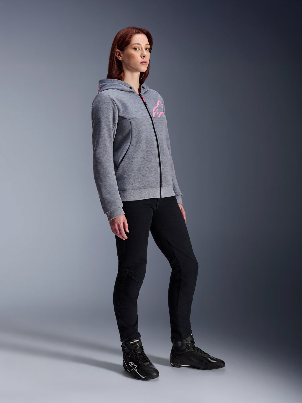 Alpinestars Stella Chrome V2 Sport hættetrøje, motorcykel-hættetrøje til kvinder, gråmeleret og neon pink, kombineret med sorte kørebukser og sorte støvler, afslappet urbant køreudstyr