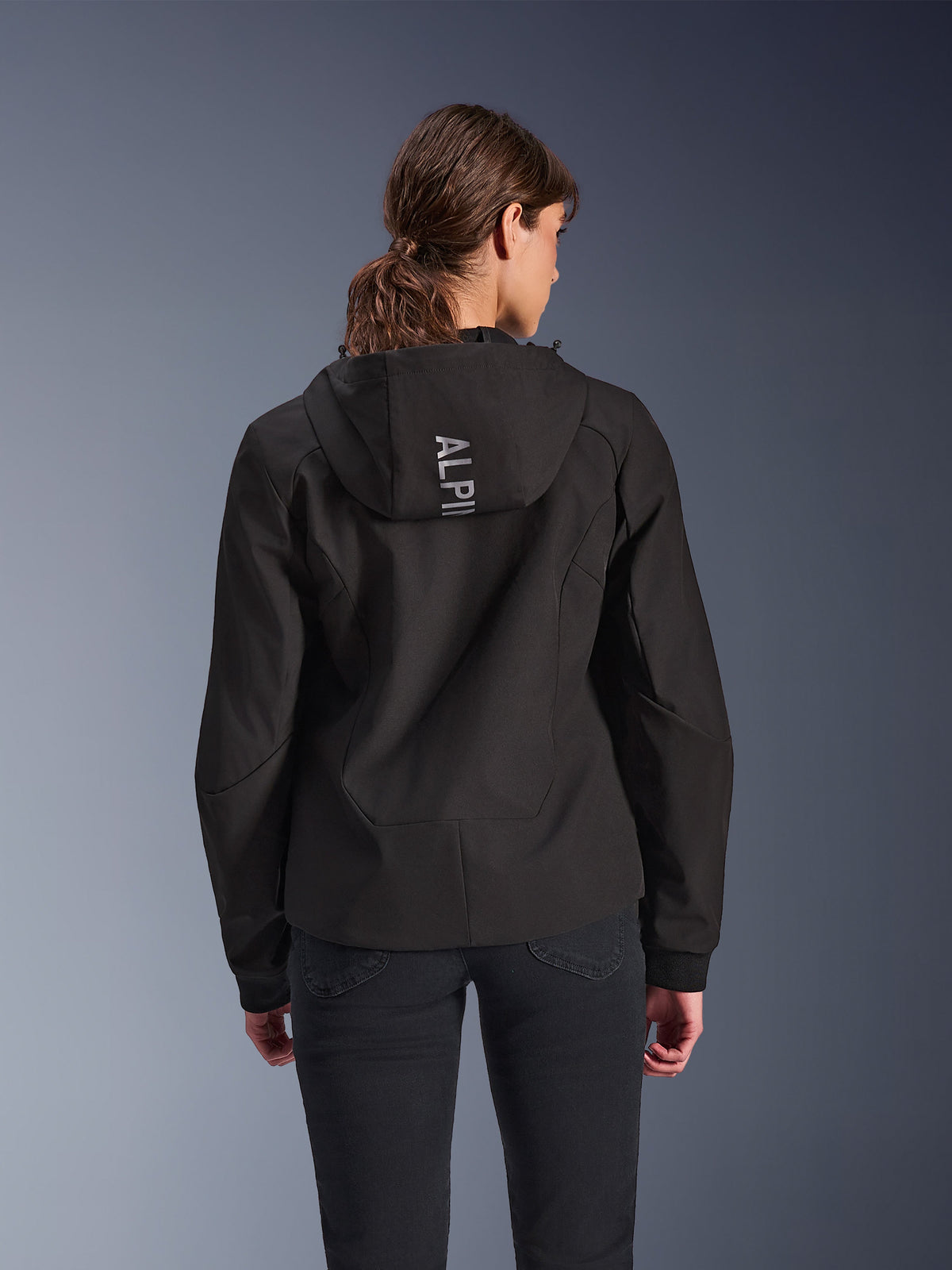 Alpinestars Stella Radium Tech Hoodie, urban motorcykelhættetrøje til kvinder i sort, set bagfra med hætte og lodret sølvfarvet Alpinestars-branding, letvægts 3-lags vindtæt skal, moderne atletisk pasform