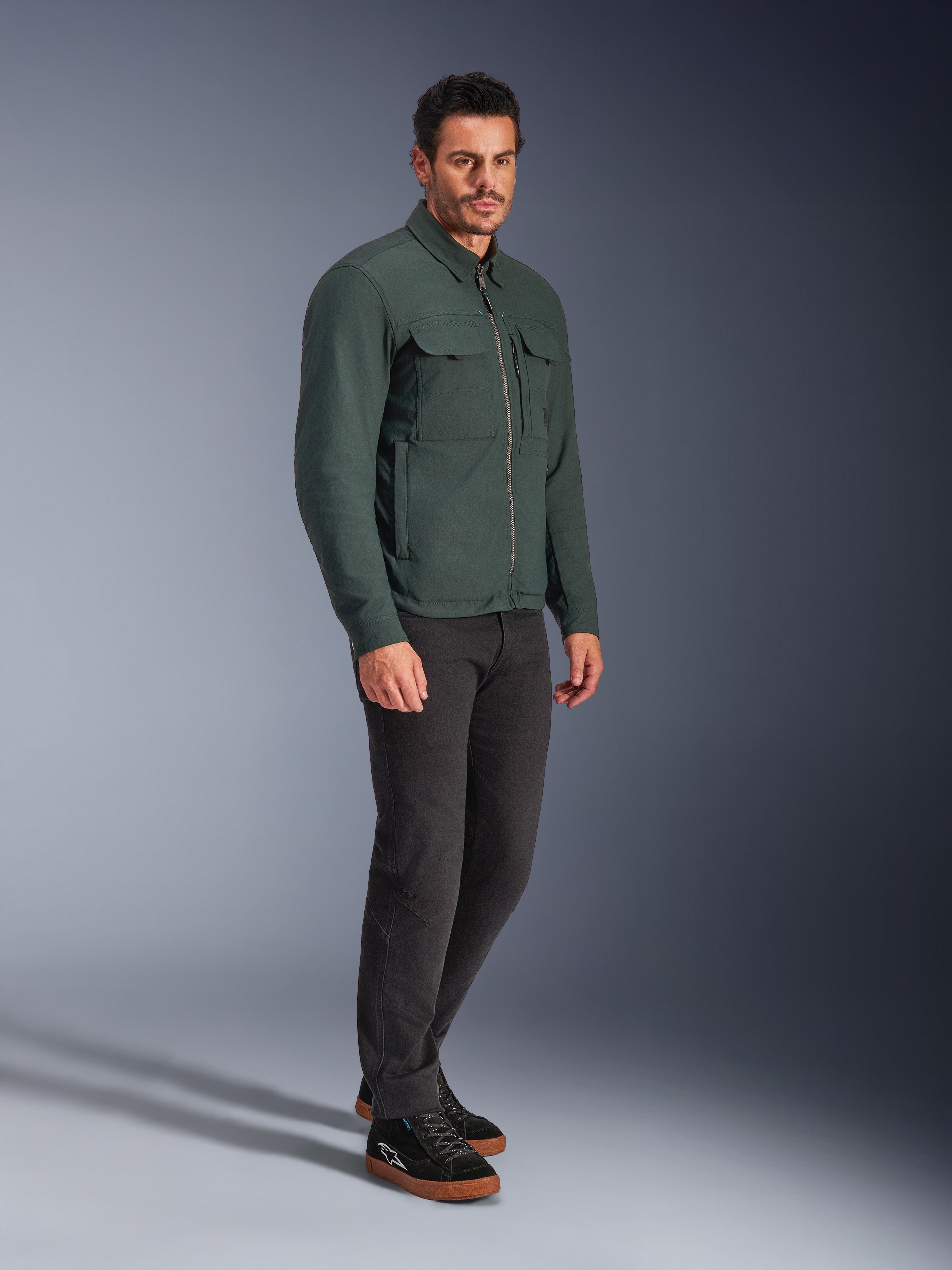 Alpinestars Bryon WR Overshirt, Dark Emerald motorcykeljakke, vandafvisende vokset lærred med cargolommer på brystet og lynlås foran, båret af en model med mørke bukser og sorte sneakers, moderne urbant køreudstyr