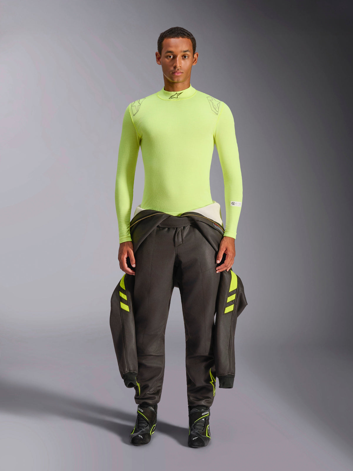 Alpinestars ZX Evo V3 langærmet top, gul fluo, vist på en model med mørke racerbukser og støvler, med halvhøj krave og atletisk pasform, brandhæmmende base layer til professionel motorsport