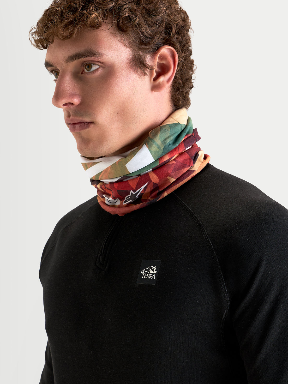 Alpinestars Buff Peaks Primaloft halsedisse, jordbrun og flerfarvet mønstret halsedisse båret af mandlig model med PrimaLoft-isolering til motorcykelkørsel i alt terræn