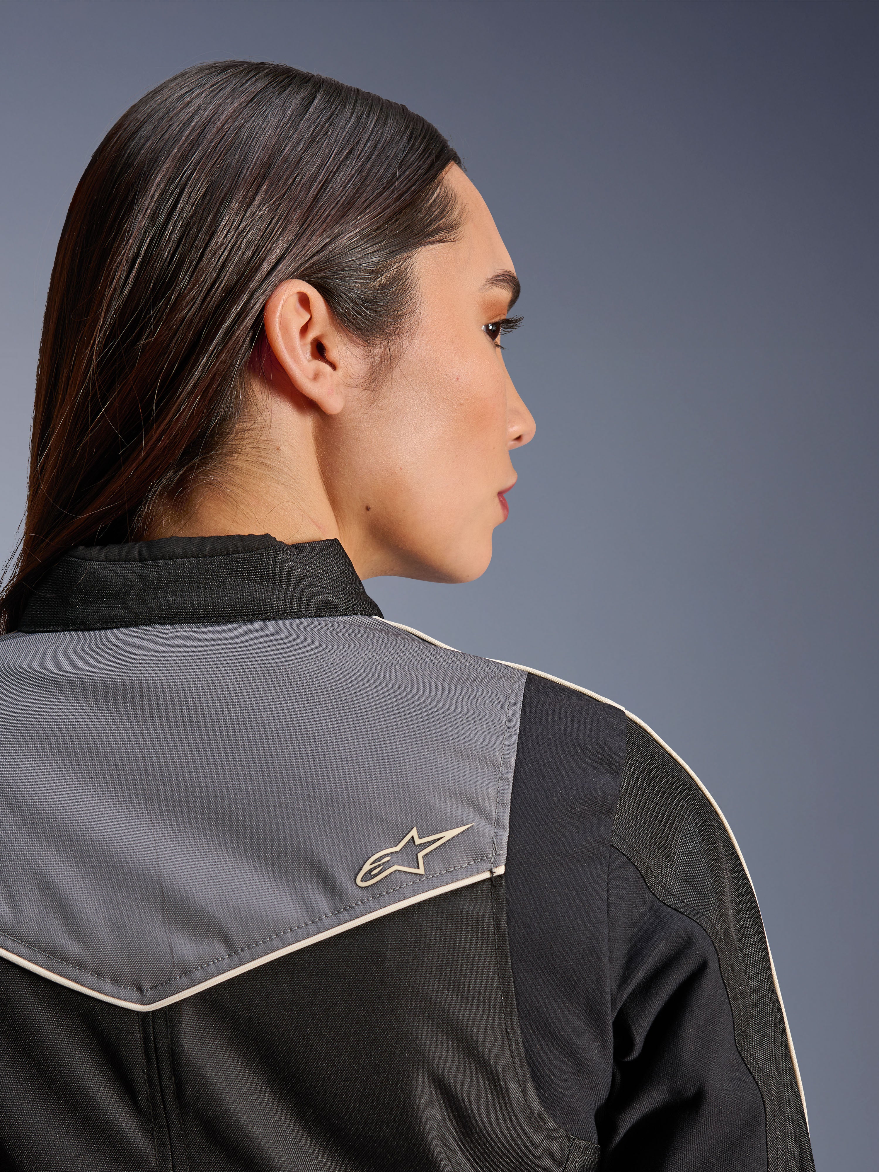 Alpinestars Stella T-Dyno WR-jakke, motorcykeljakke til kvinder, sort, mørkegrå og ecru, nærbillede bagfra af skulder og bærestykke med gråt panel og ecru stjernelogo, vintage-inspireret køreudstyr
