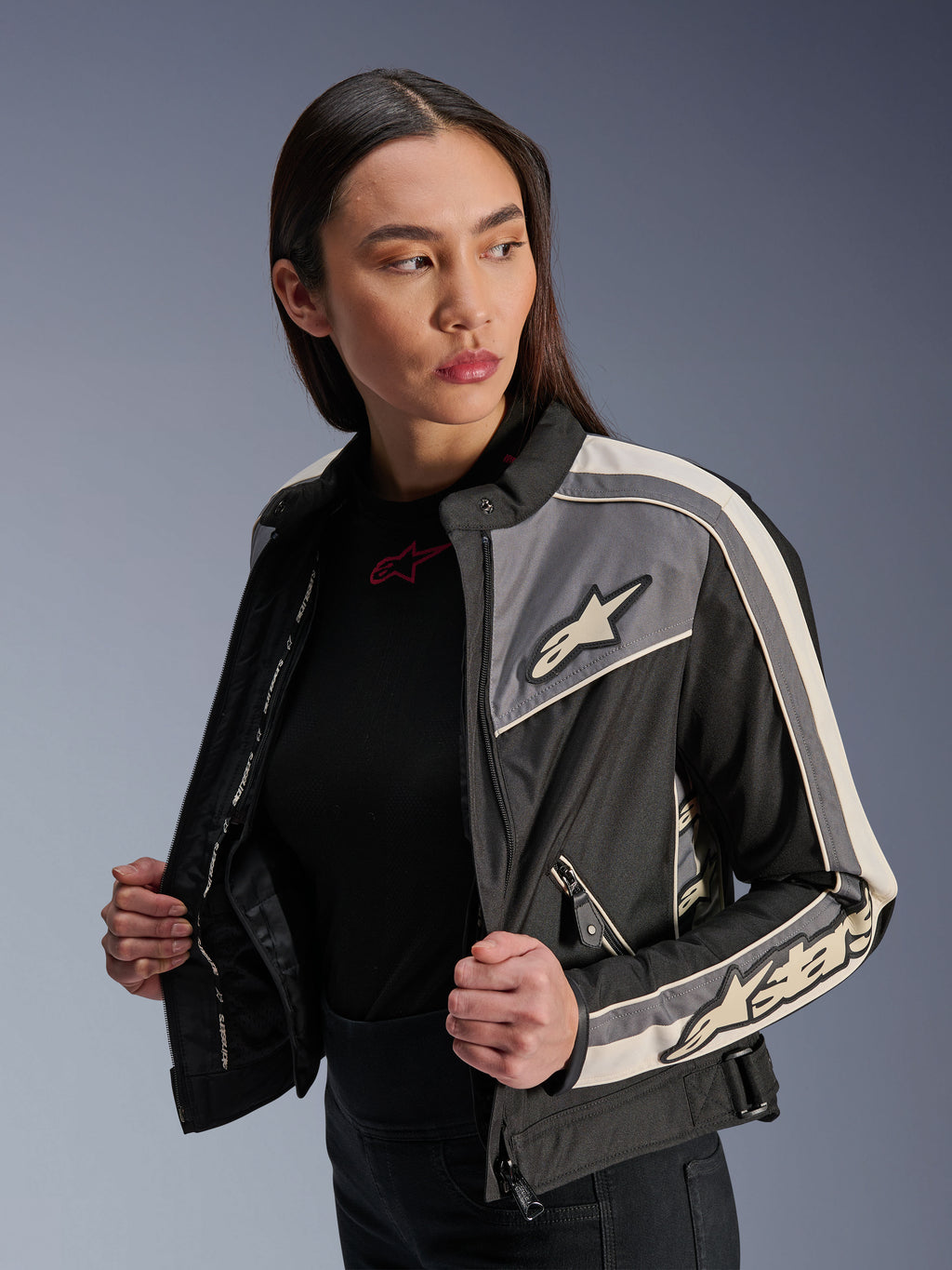 Alpinestars Stella T-Dyno WR jakke til kvinder, tekstil motorcykeljakke, sort, mørkegrå og ecru, vintage-inspireret design med sporty striber og logoer på bryst og ærmer, båret af en model, urbant udstyr til vej