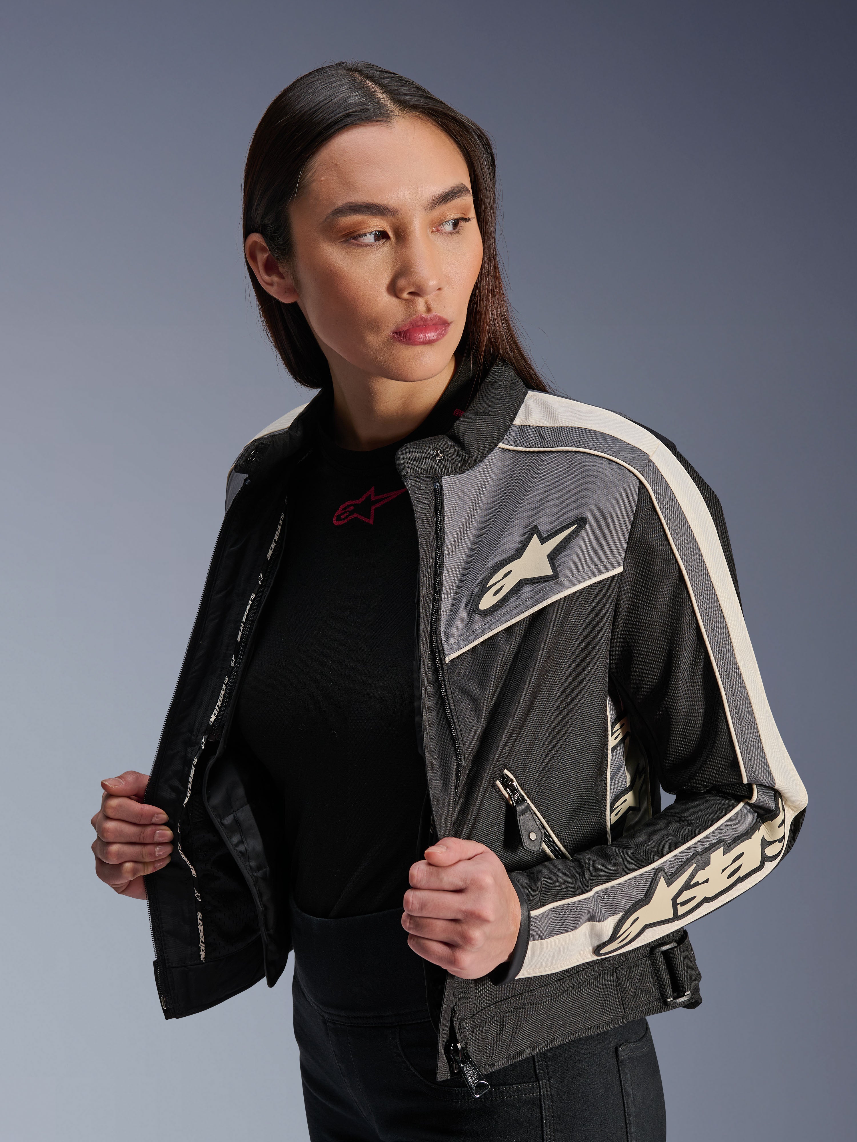 Alpinestars Stella T-Dyno WR jakke til kvinder, tekstil motorcykeljakke, sort, mørkegrå og ecru, vintage-inspireret design med sporty striber og logoer på bryst og ærmer, båret af en model, urbant udstyr til vej
