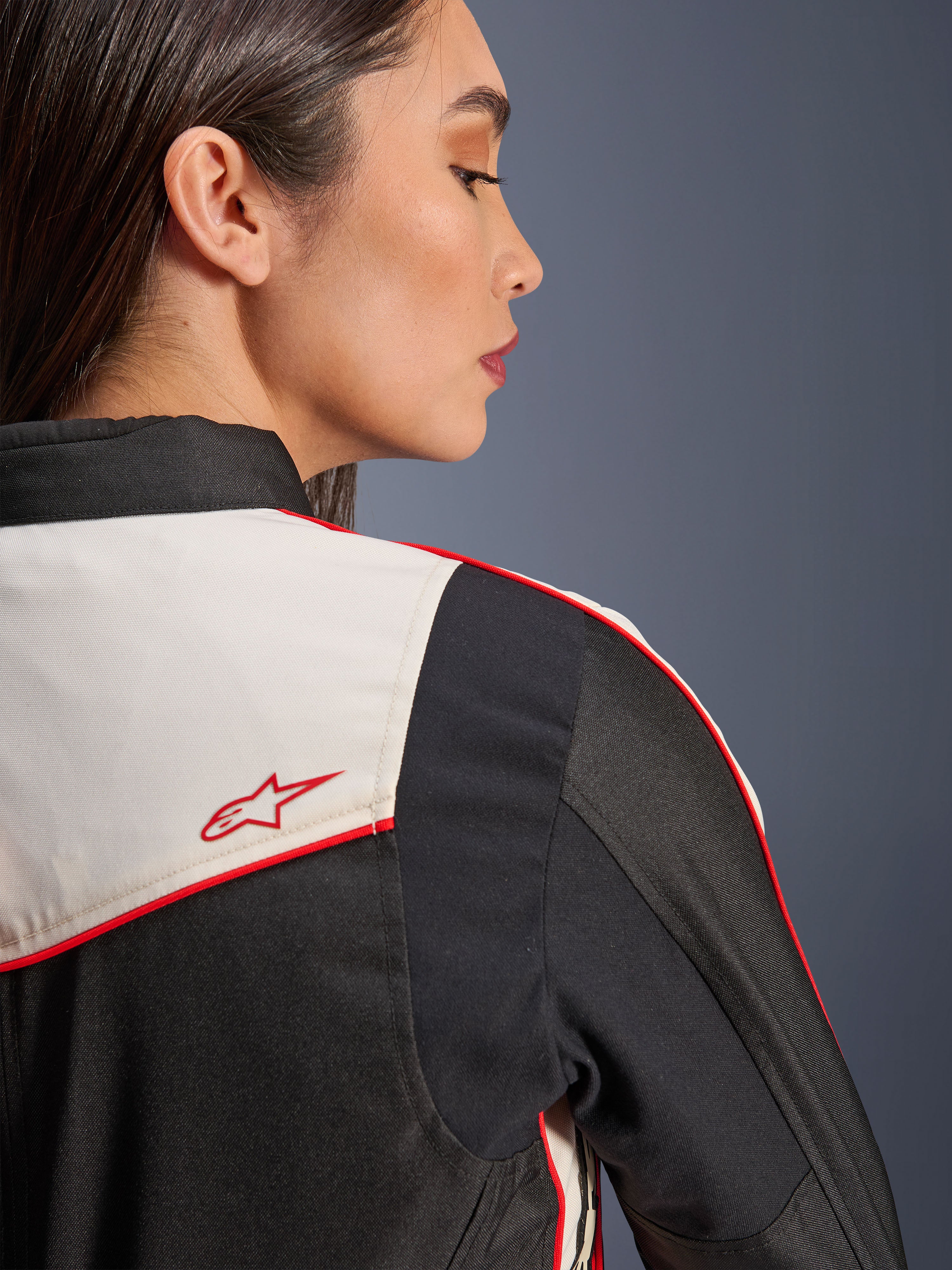 Alpinestars Stella T-Dyno WR-jakke i Black Ecru Bright Red, nærbillede af skulderen og ryggen, med ecru-paneler, røde tittekanter og et rødt Alpinestars-stjernelogo, tekstilmotorcykeludstyr til kvinder