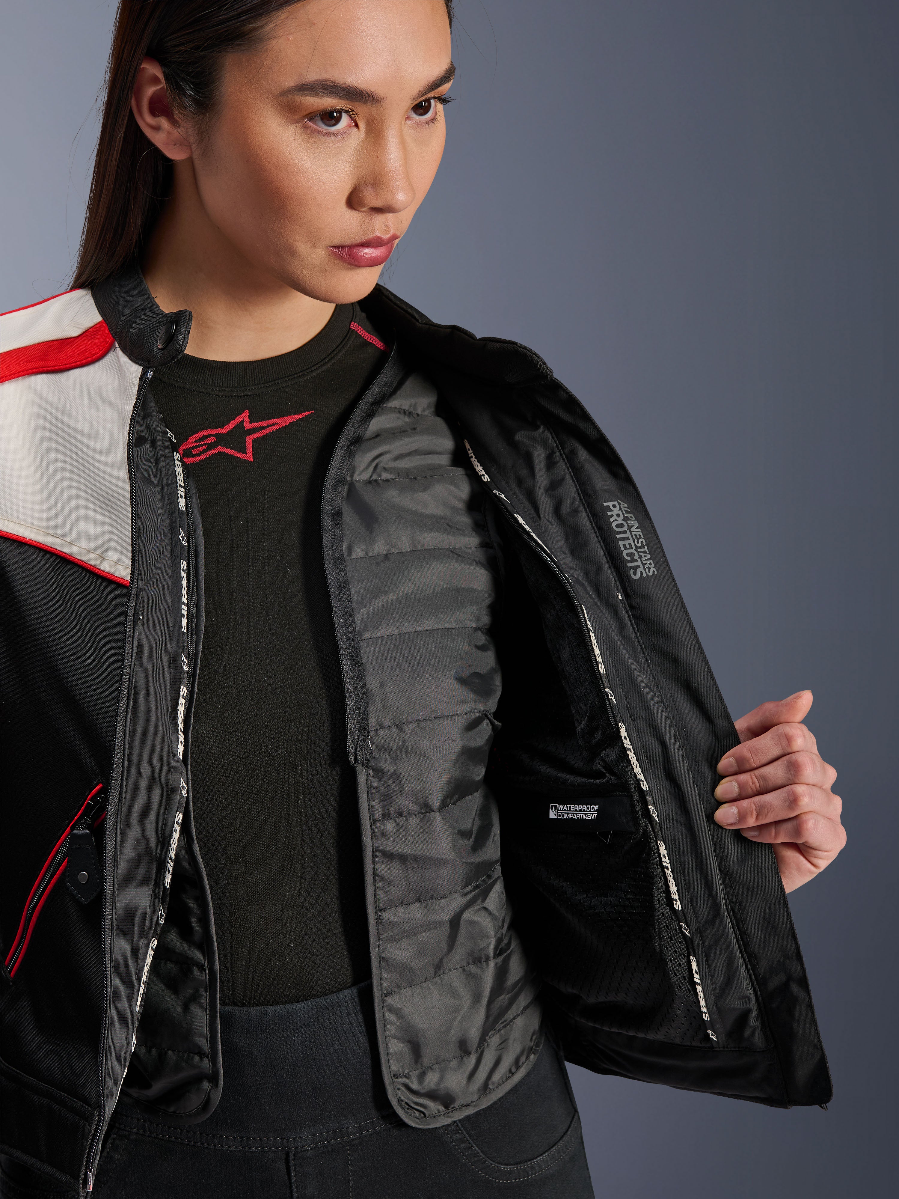 Alpinestars Stella T-Dyno WR jakke, motorcykeljakke til damer, sort, ecru og klar rød, nærbillede af indersiden, der viser den aftagelige quiltede termovest, vandtæt indvendigt rum og 'ALPINESTARS PROTECTS' branding.