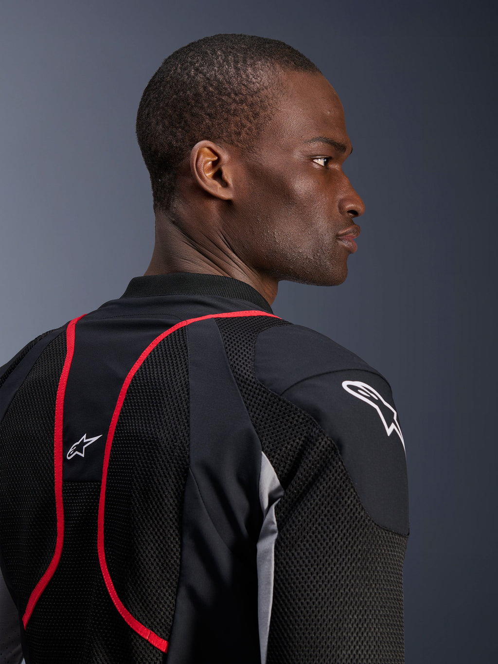 Alpinestars Troop-Air Pro-jakke, teknisk pansret luftjakke, sort, askegrå og lysende rød, nærbillede af profil og rygvisning, der viser mesh-tekstilpaneler, røde piping-detaljer og hvide Astars-logoer på skulderen og den øverste del af ryggen