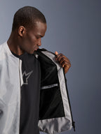 Mandlig model iført Alpinestars C-1 Air Jakke i sølv, der åbner fronten for at vise det sorte tech mesh-inderfor og en vandtæt inderlomme med lynlås.