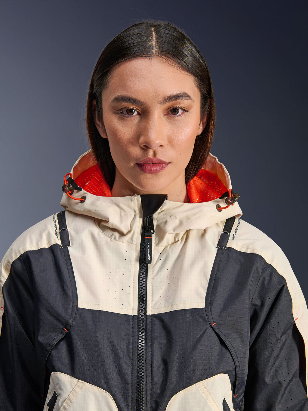 Alpinestars Molly Air-jakke, tekstil-motorcykeljakke til damer, Black Almond, nærbillede forfra af en model iført jakken med et creme- og sort paneldesign, klar orange mesh-foret hætte og laserperforerede detaljer på brystet