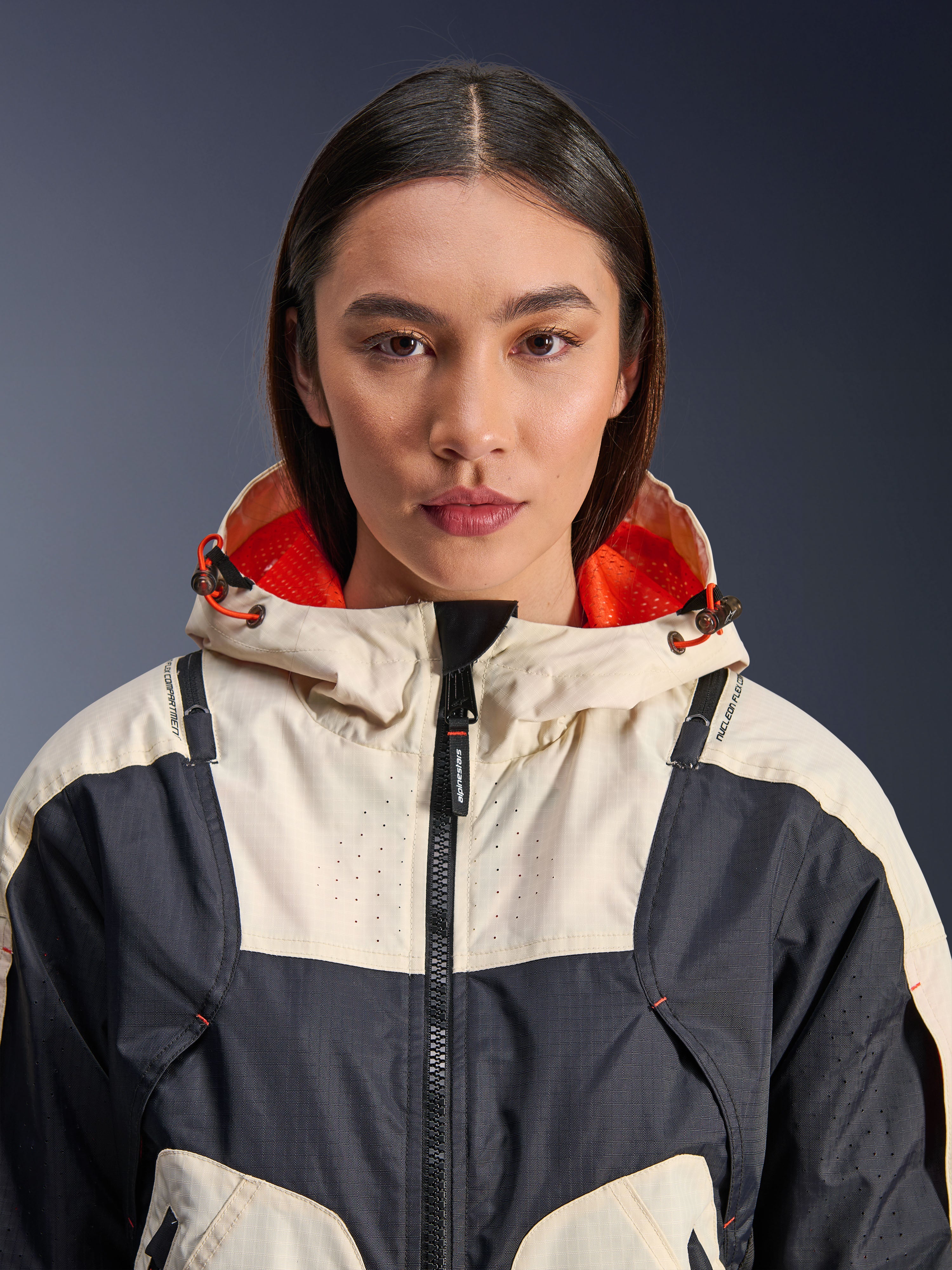 Alpinestars Molly Air-jakke, tekstil-motorcykeljakke til damer, Black Almond, nærbillede forfra af en model iført jakken med et creme- og sort paneldesign, klar orange mesh-foret hætte og laserperforerede detaljer på brystet